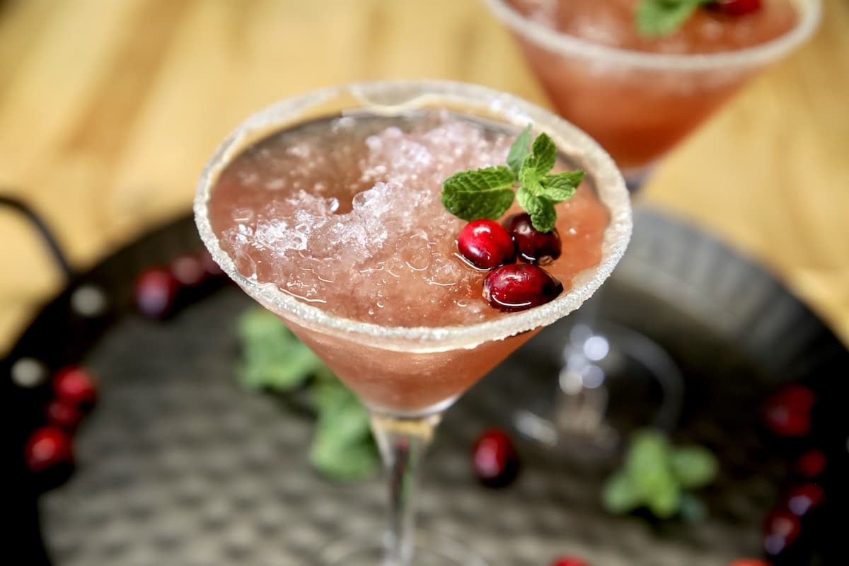 Cranberry slush cocktail with cranberry and mint garnish.