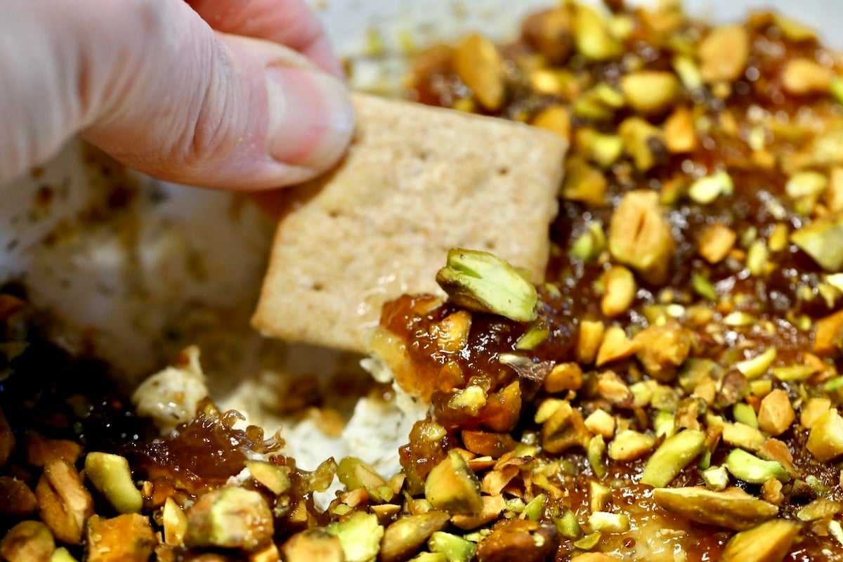Fig and boursin dip on a cracker - held in hand.
