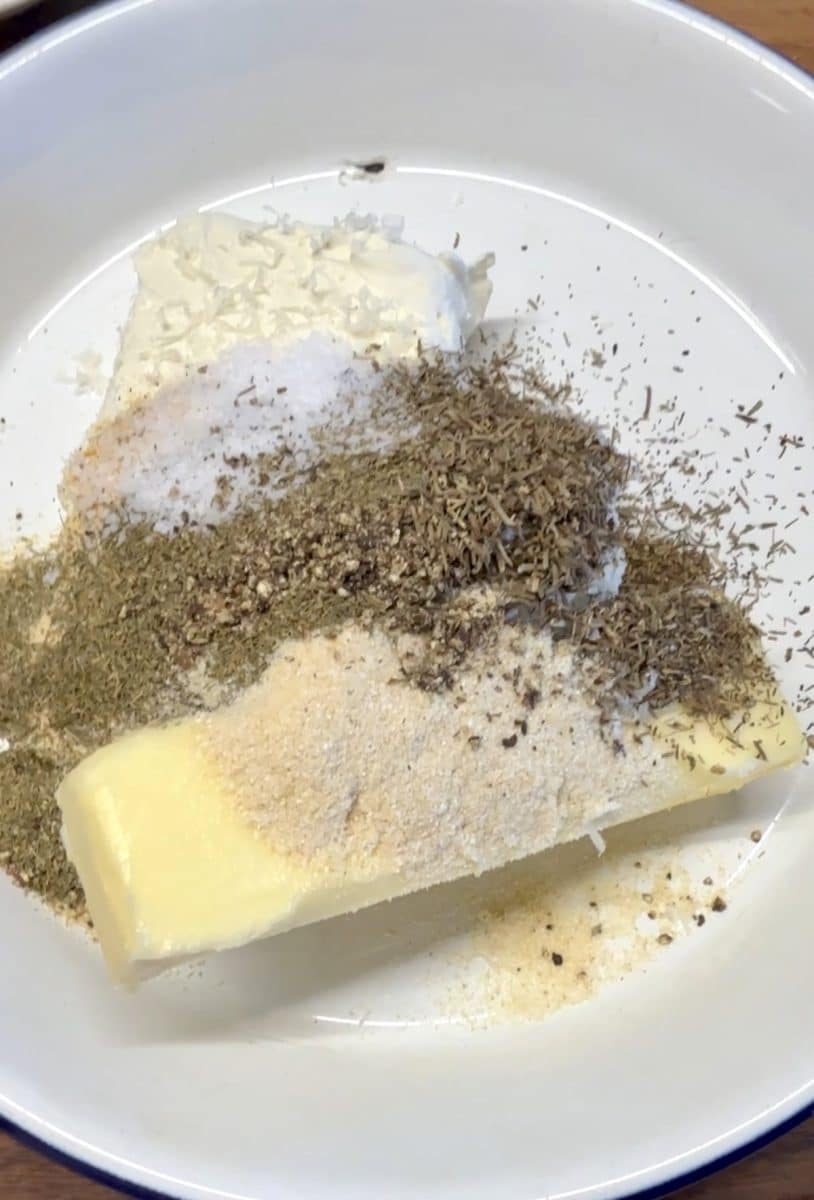 Herbs, parmesan, butter and cream cheese in a bowl.