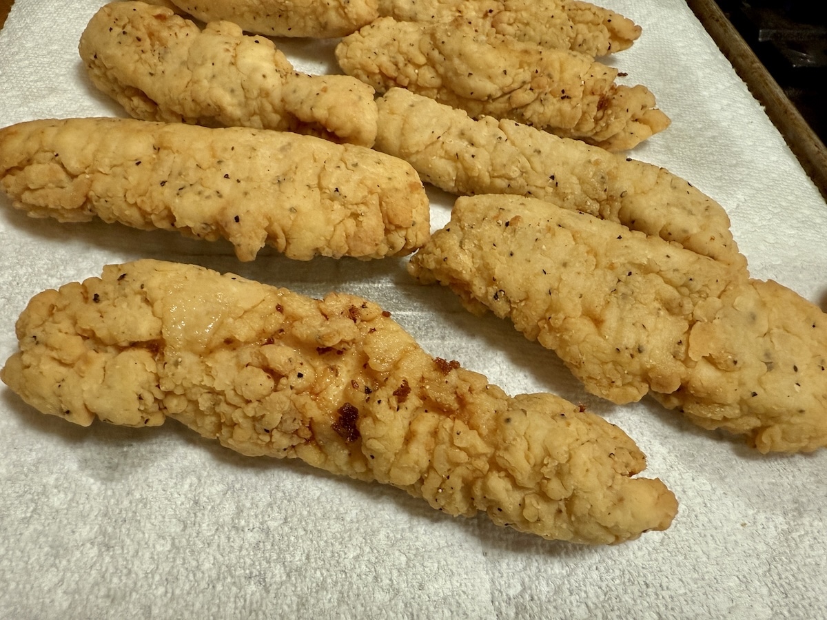 Fried Chicken tenders draining on paper towel.