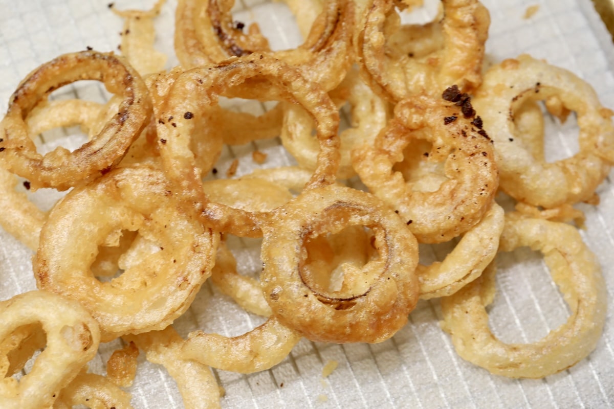 Beer battered onion rings draining on paper towel.