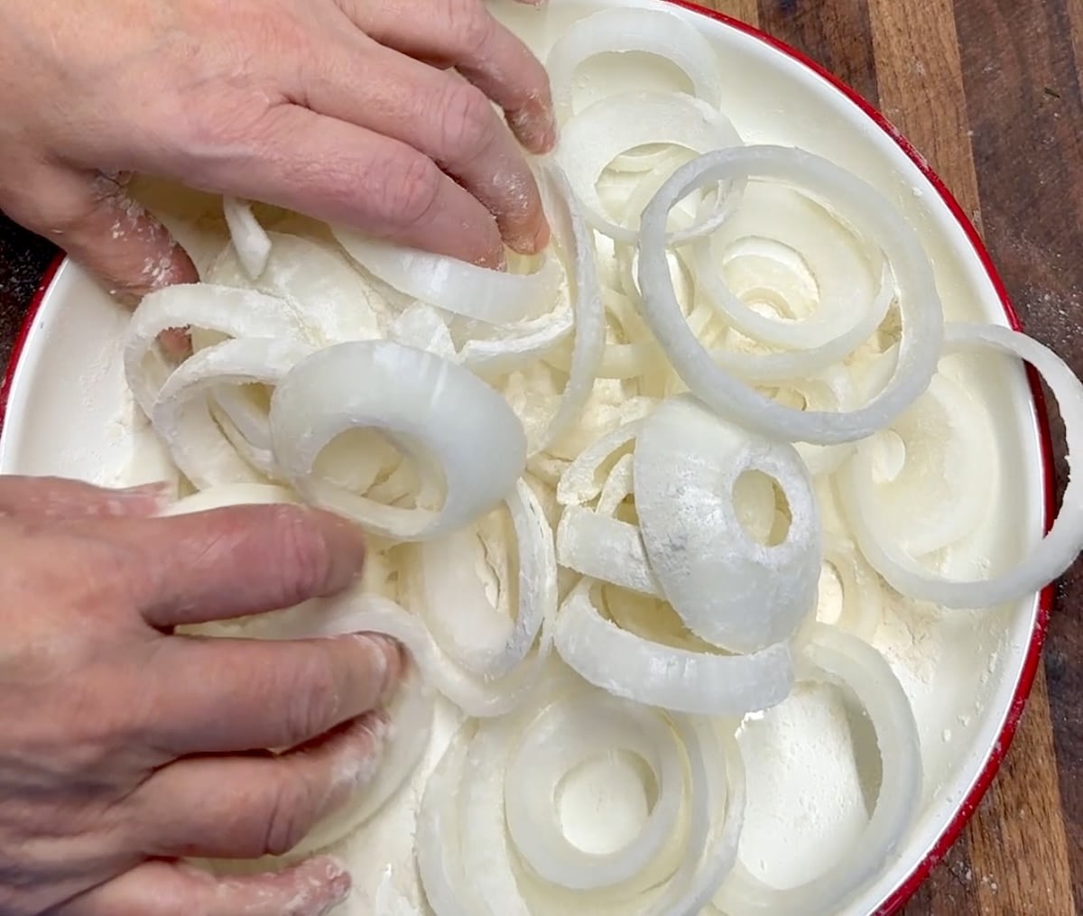 Tossing onion rings with flour.
