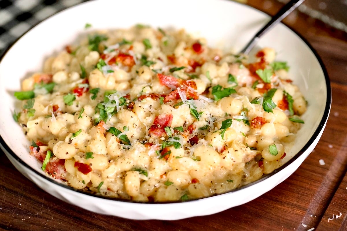 Bacon and parmesan white beans. Bowl of carbonara beans with bacon and parmesan.