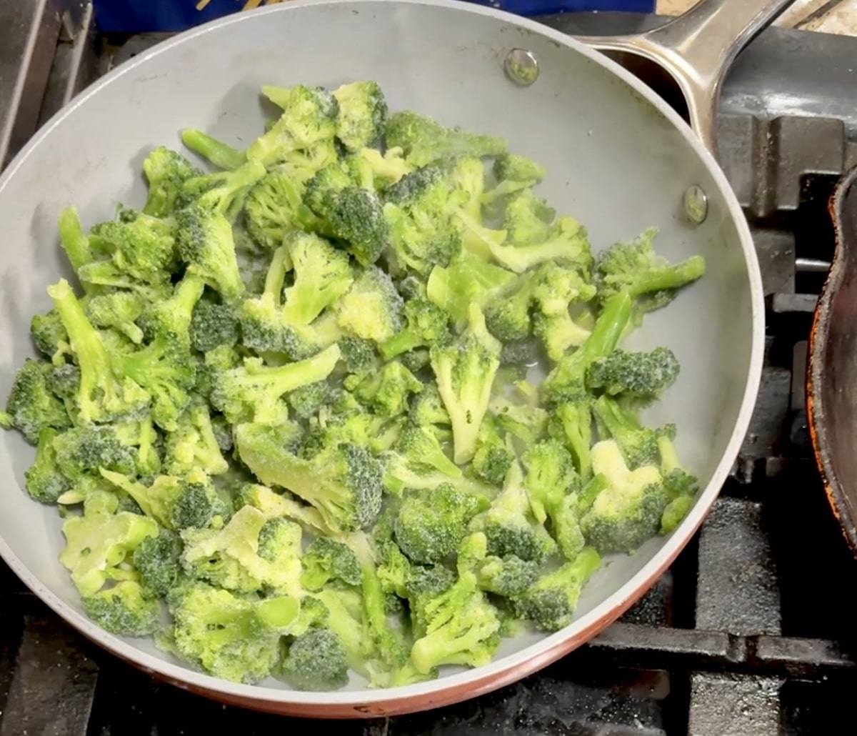 Cooking frozen broccoli in a pan.