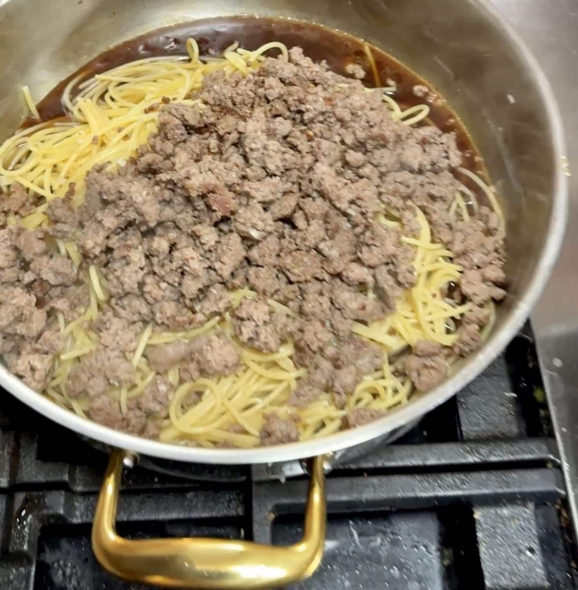 Spaghetti and ground beef in a pan with sesame sauce.