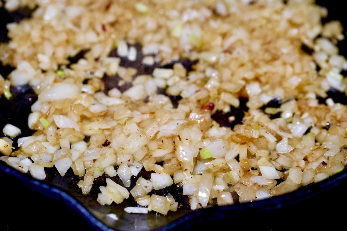 Diced onions cooking in a skillet.
