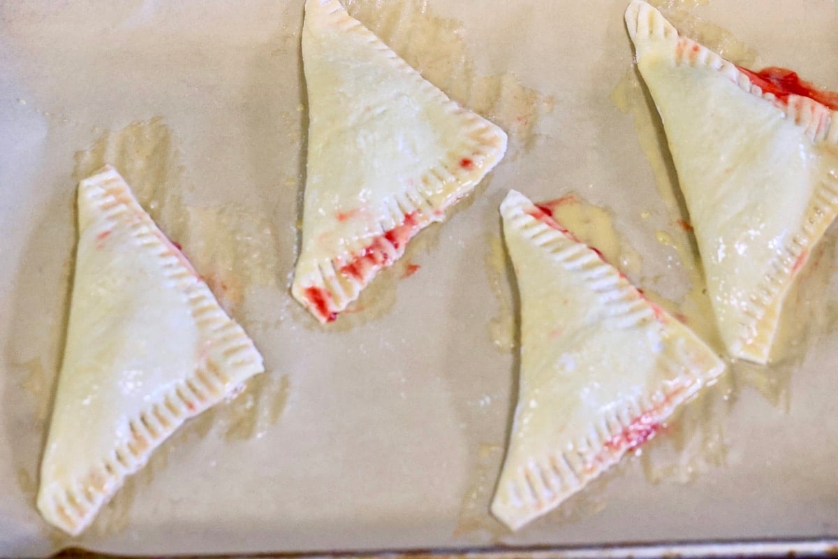 Puff pastry triangles on a baking sheet.