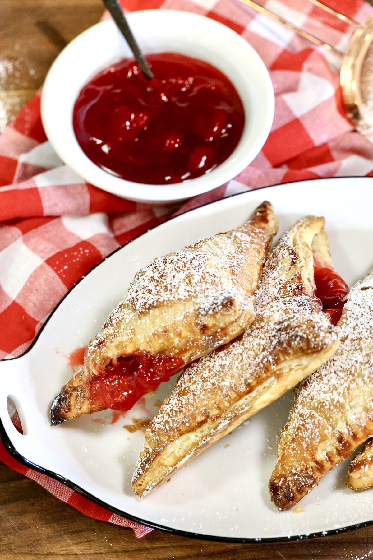 Platter of strawberry turnovers with bowl of strawberry pie filling.