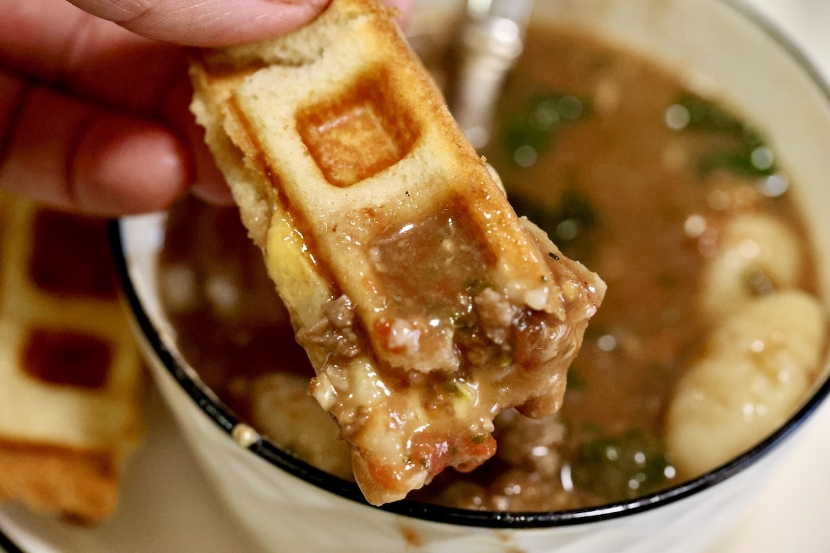 Grilled cheese waffle dipping into soup.