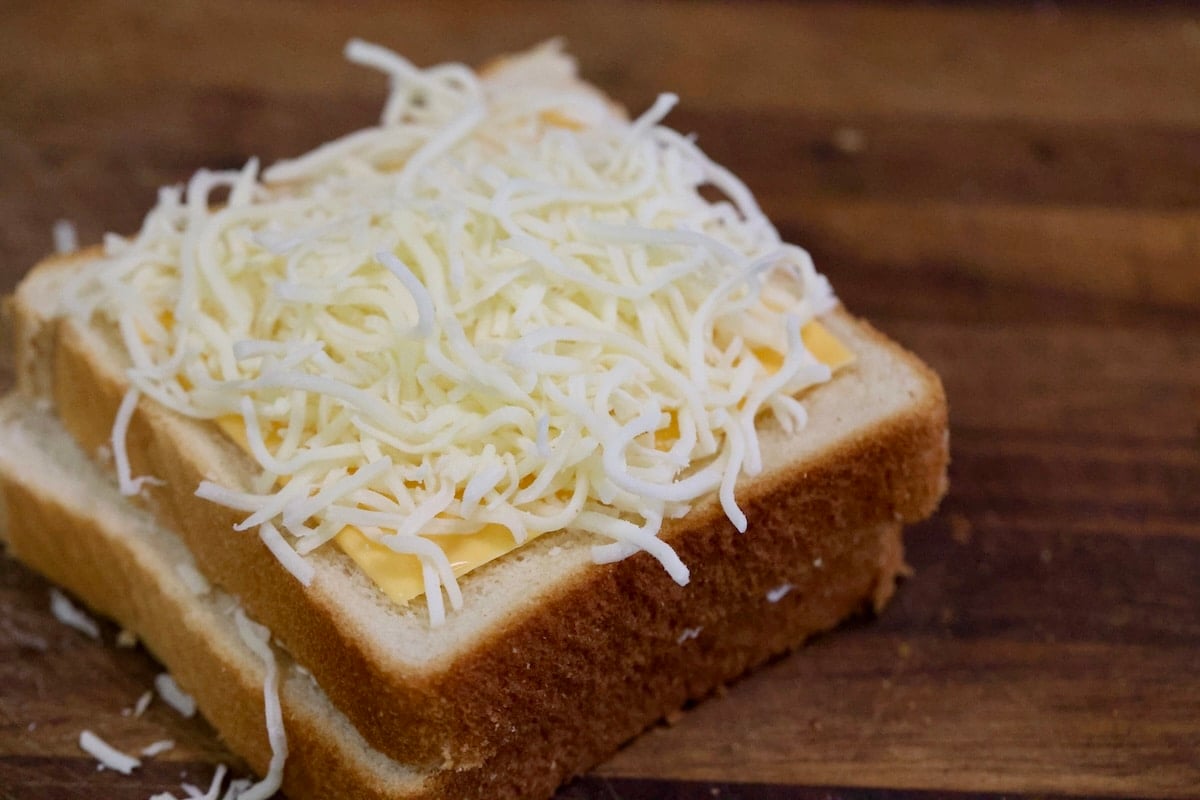 Shredded mozzarella on bread for grilled cheese.