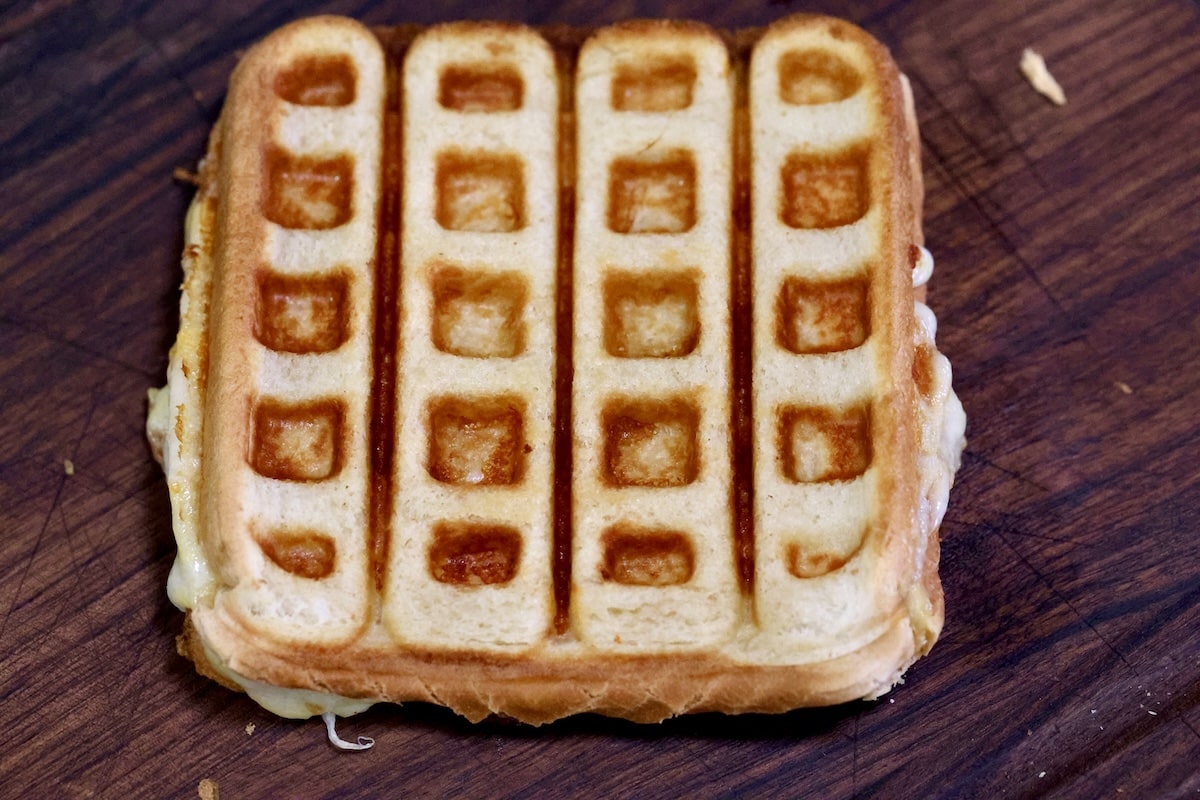 Waffle iron grilled cheese on cutting board.