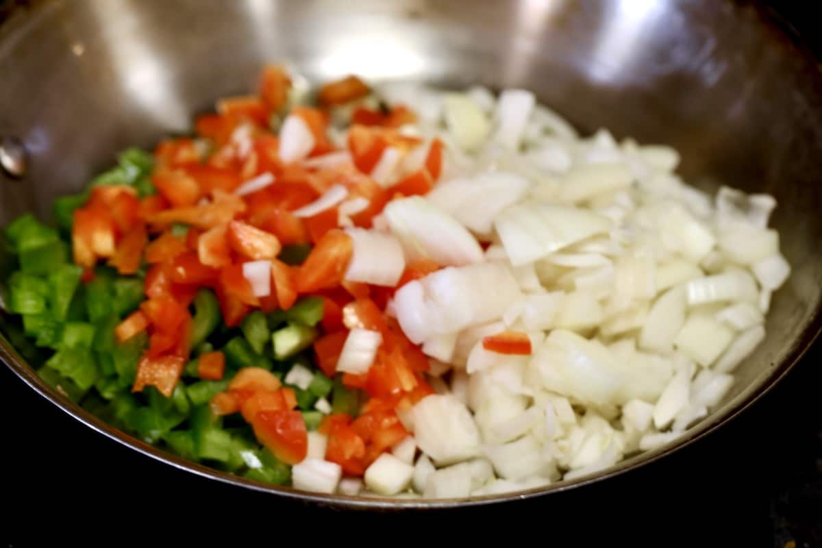 Peppers and onions in a pan to saute.