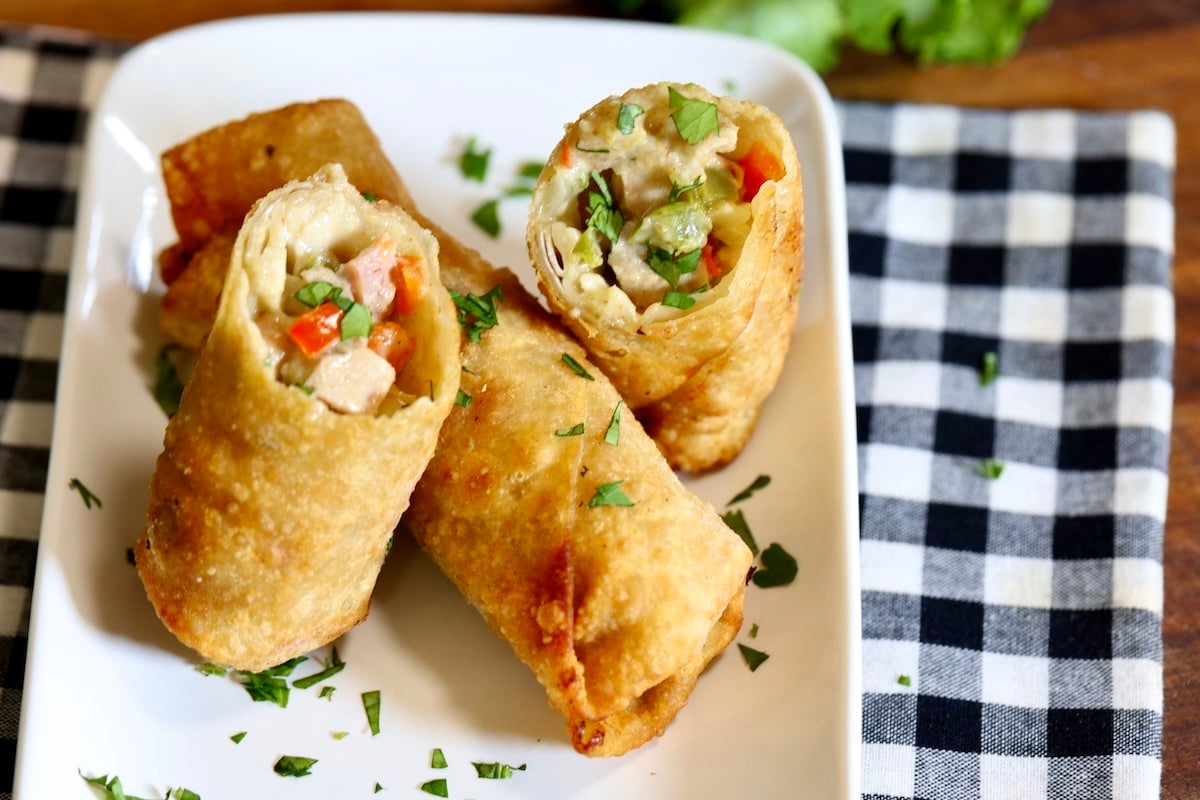 Egg rolls on a plate, one cut in half.