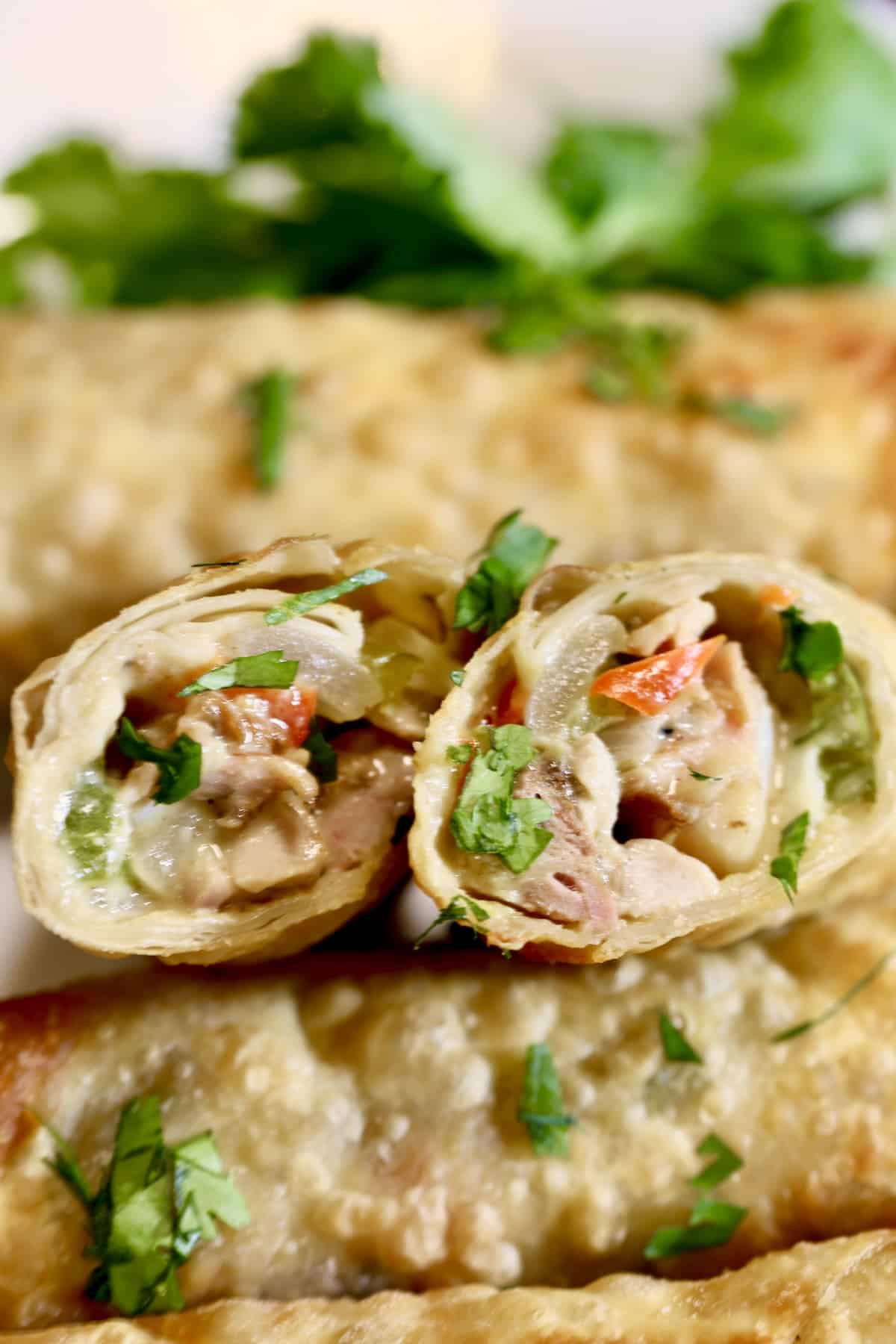 2 egg rolls on a plate, cut  in half.