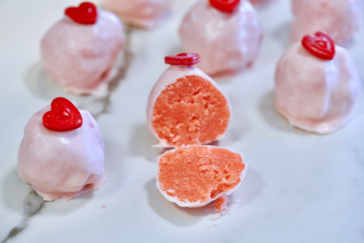 Valentine's Day cake balls with heart candies, one cut in half.
