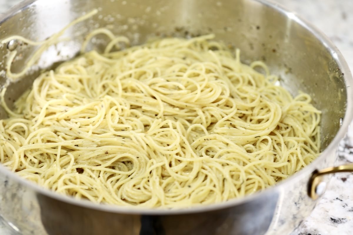 Spaghetti tossed with sauce in a pan.