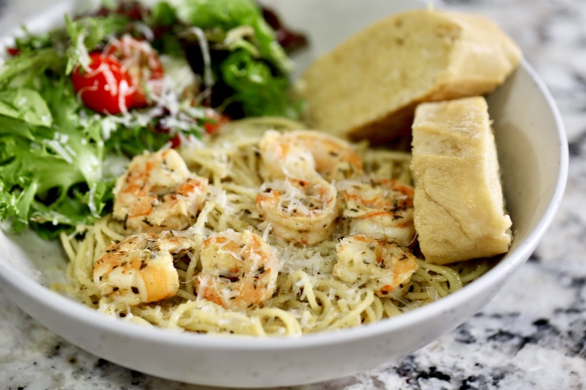Spaghetti with shrimp, salad and bread in a bowl.