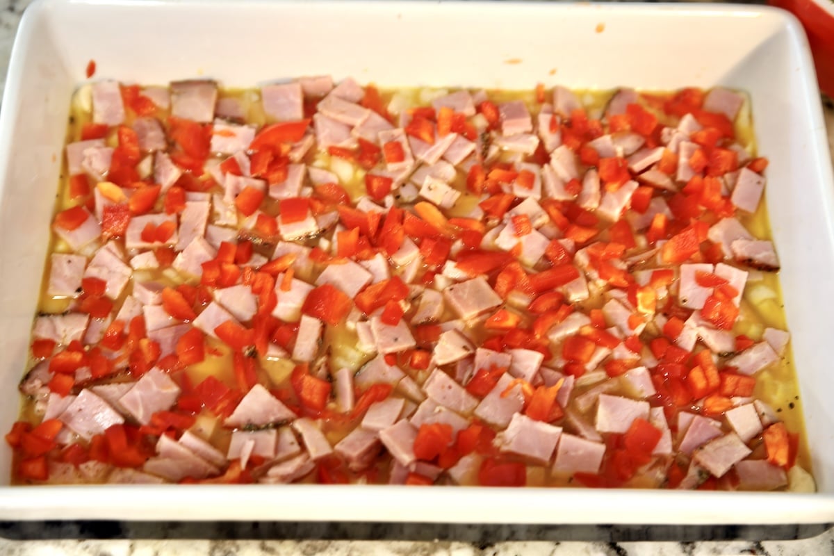Breakfast bake in a casserole with red bell peppers and ham.