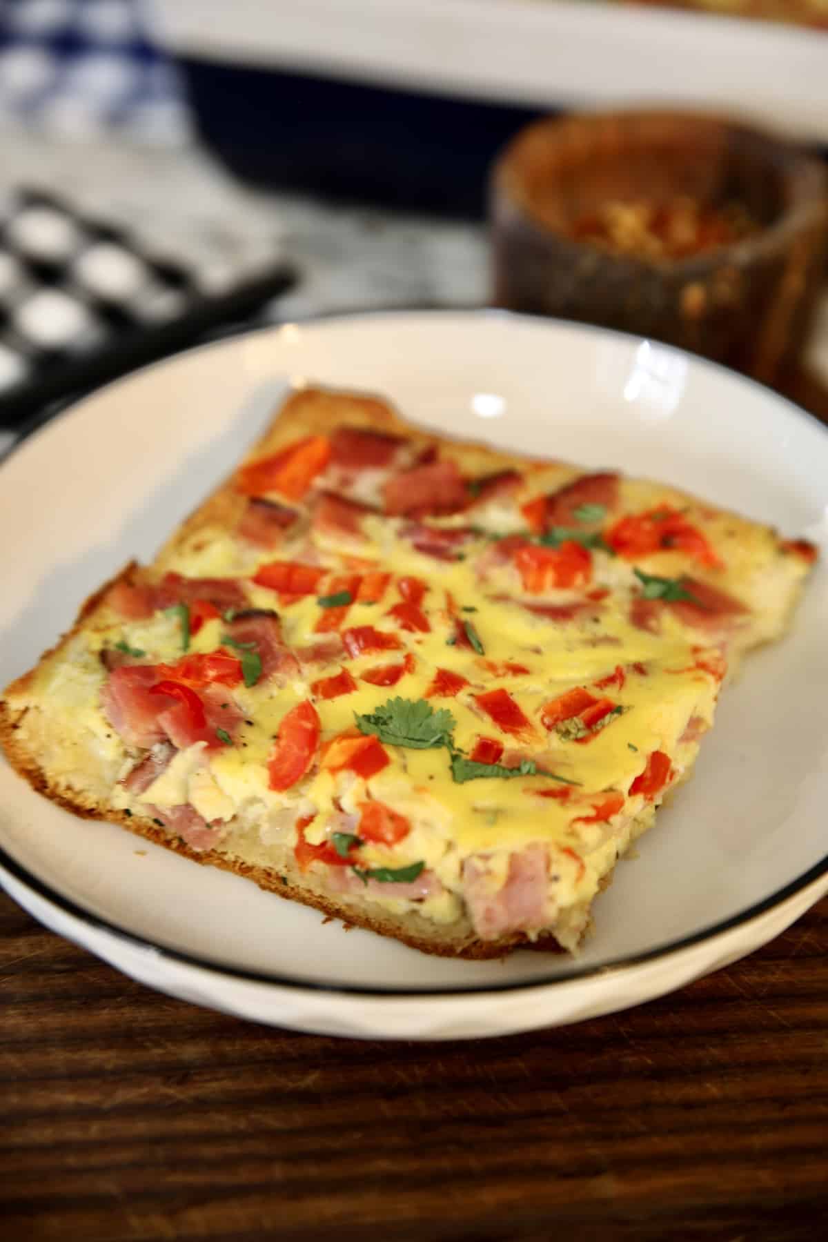 Slice of ham and egg bake on a saucer.