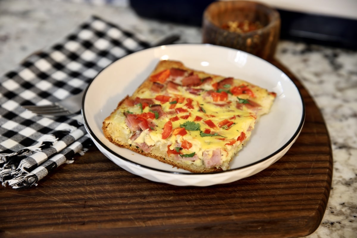 Slice of breakfast casserole on a plate with checked napkin.
