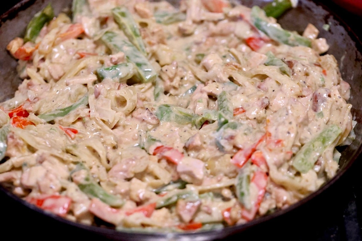 Chicken fajita mixture with cheese sauce in a pan.