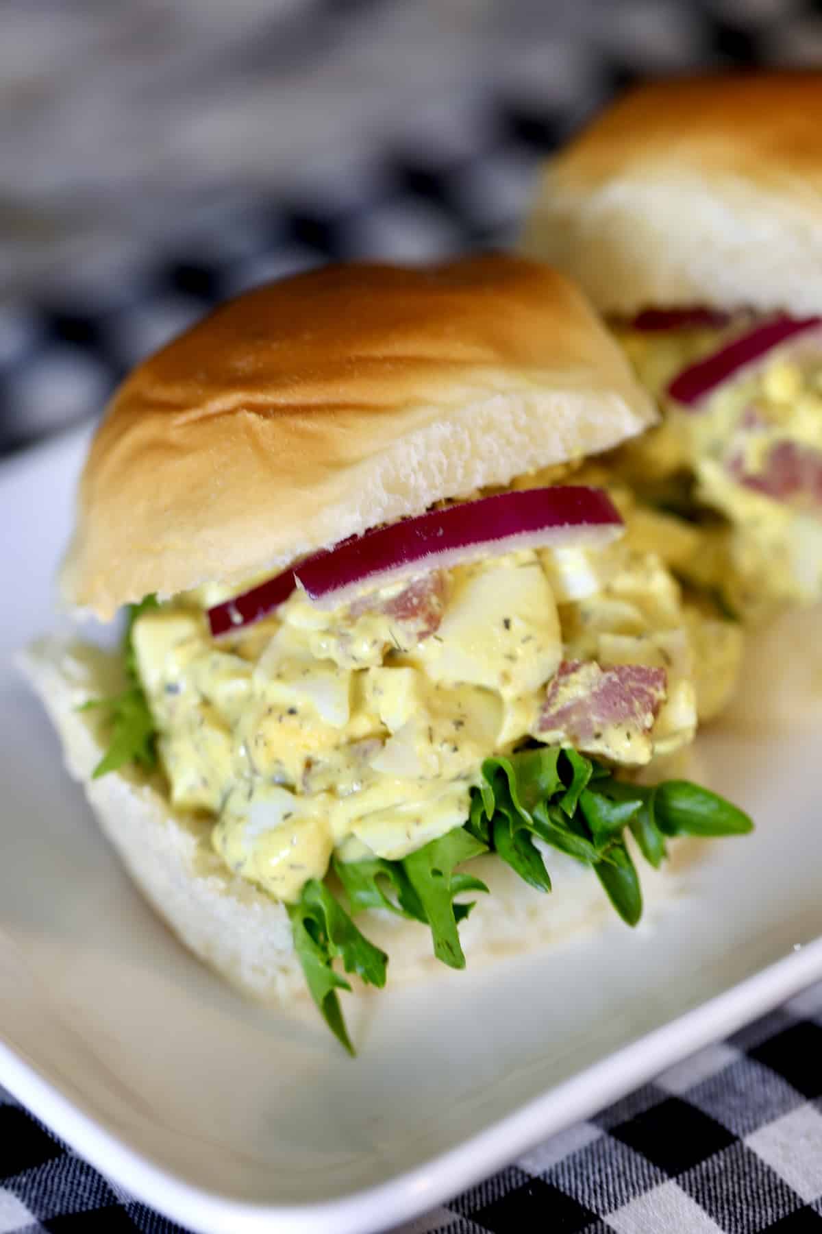 Ham and egg salad on Hawaiian rolls on a plate.