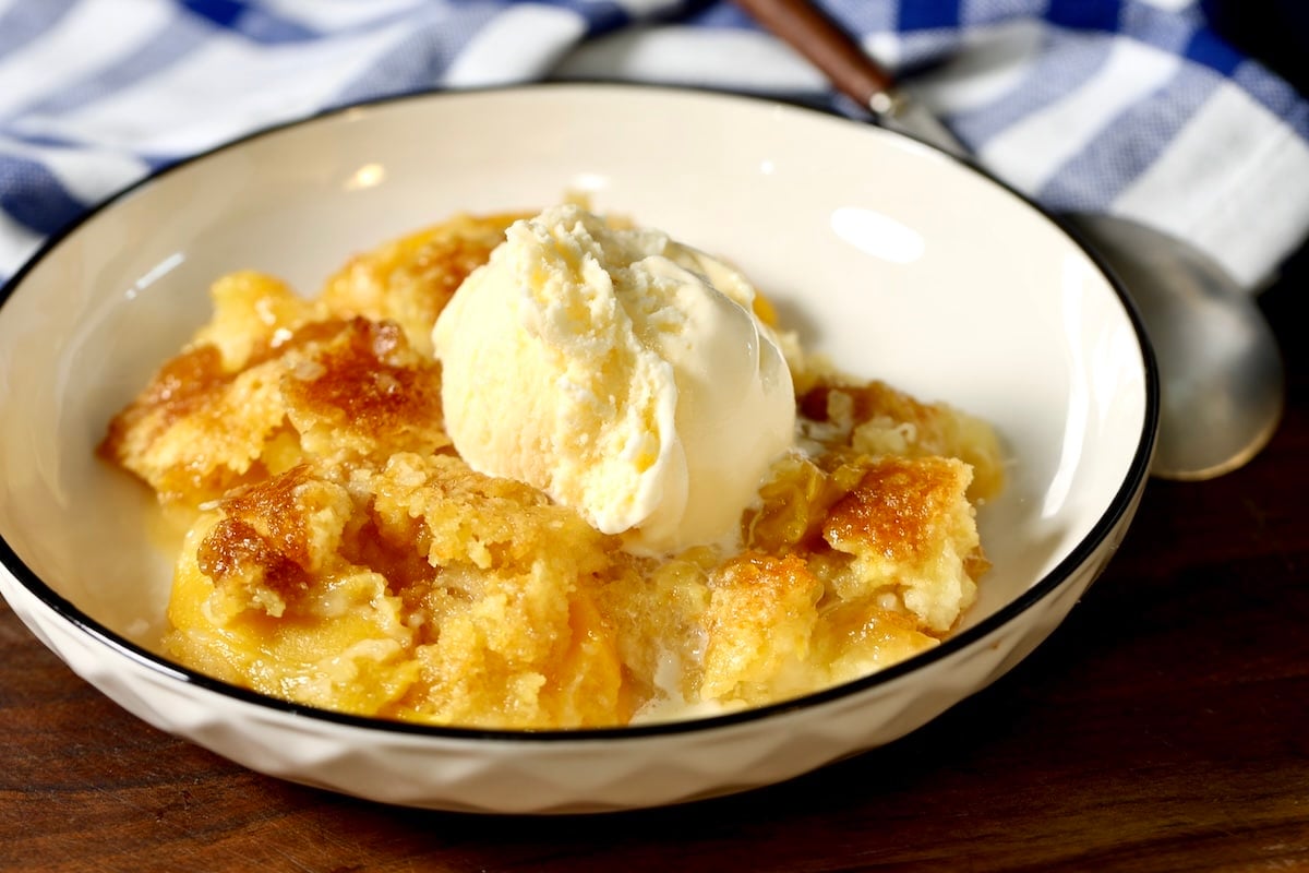 Dump cake with brown sugar topping, peach and pineapple filling. Bowl of peach and pineapple dump cake with ice cream.
