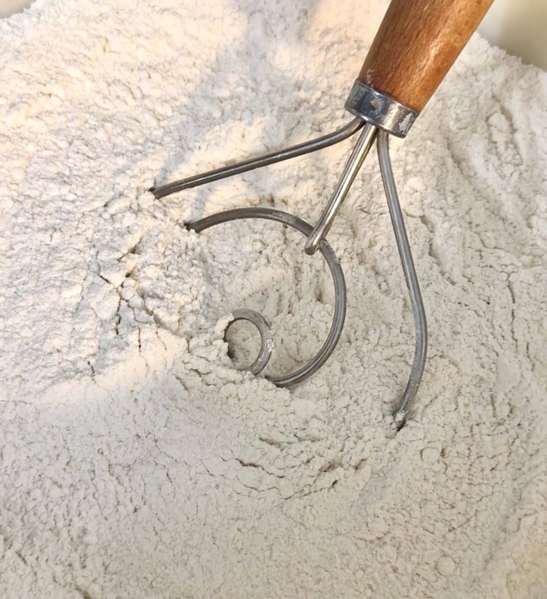 All purpose flour in a bowl for beer bread with dough whisk.