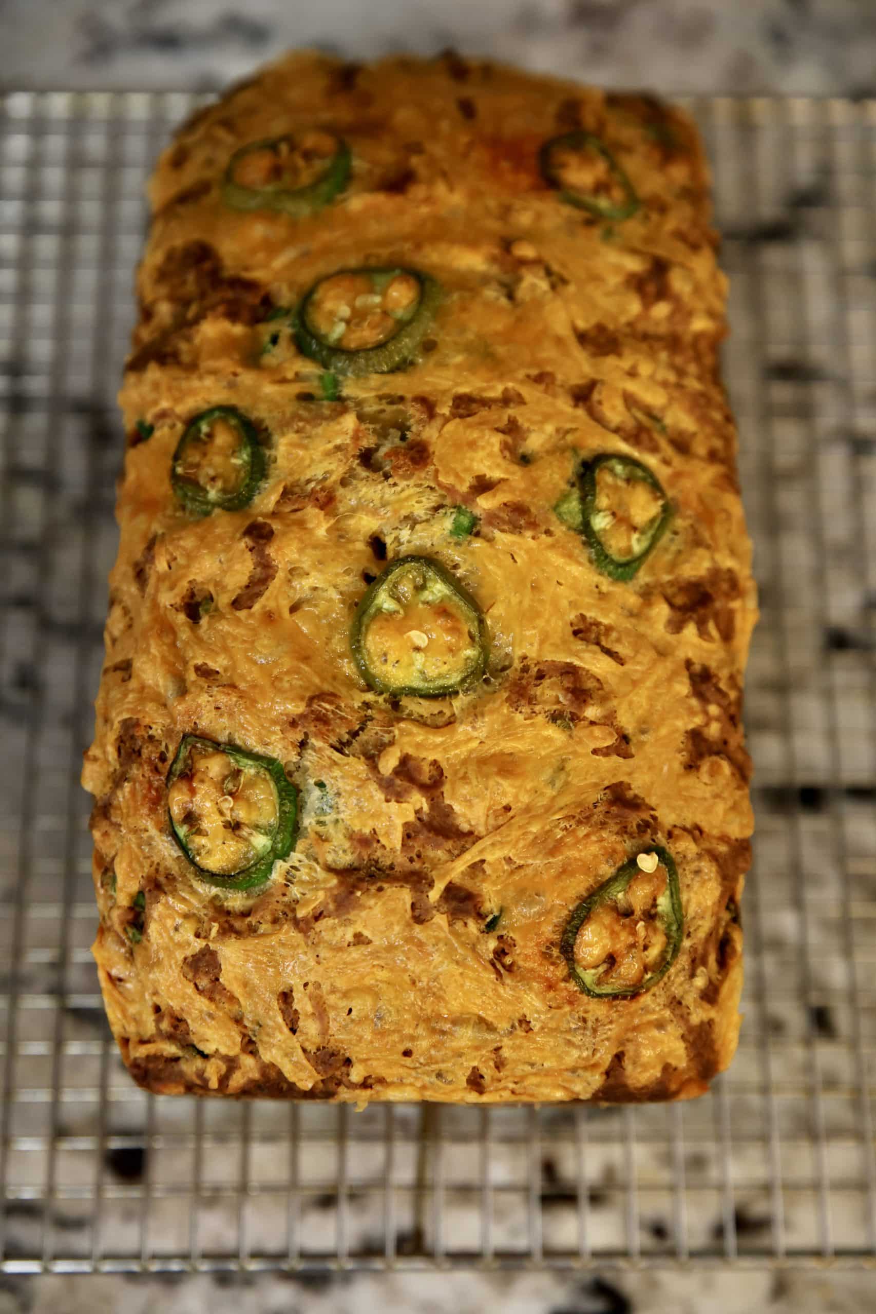 Loaf of cheddar jalapeno beer bread cooling on a wire rack.