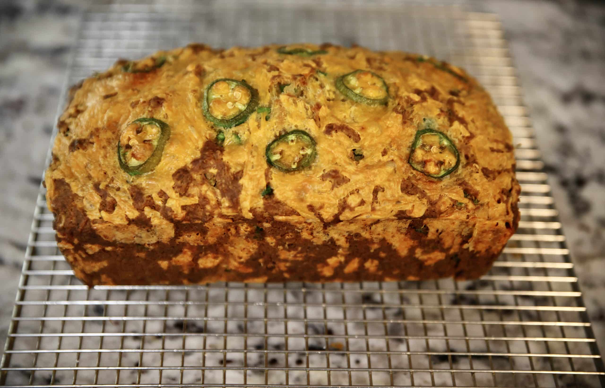 Loaf of jalapeno cheddar quick bread on a wire rack.
