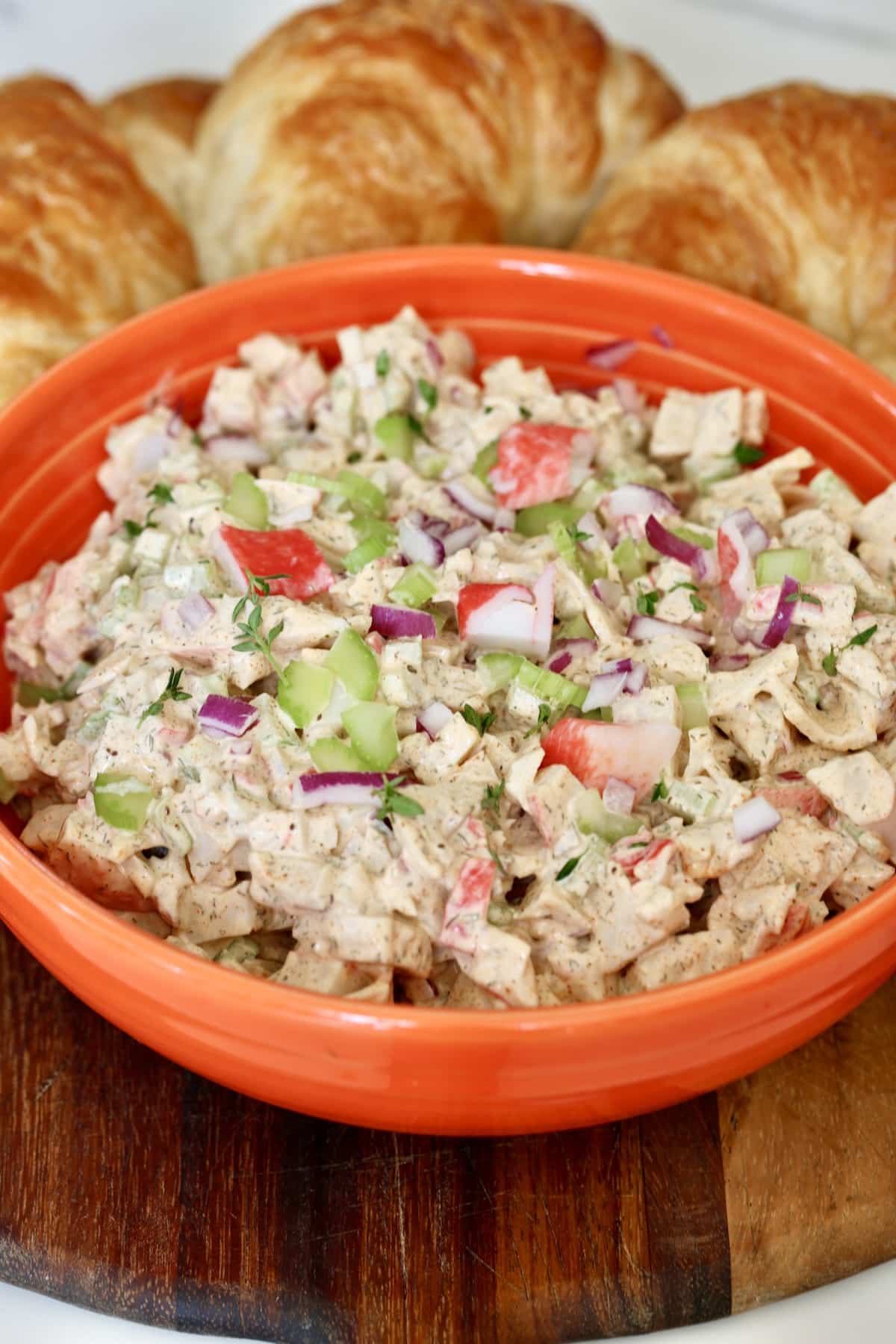 Bowl of seafood salad with croissants around the bowl.
