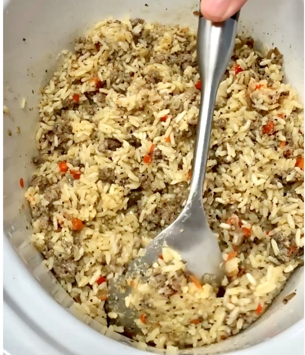Stirring dirty rice in a crock pot.