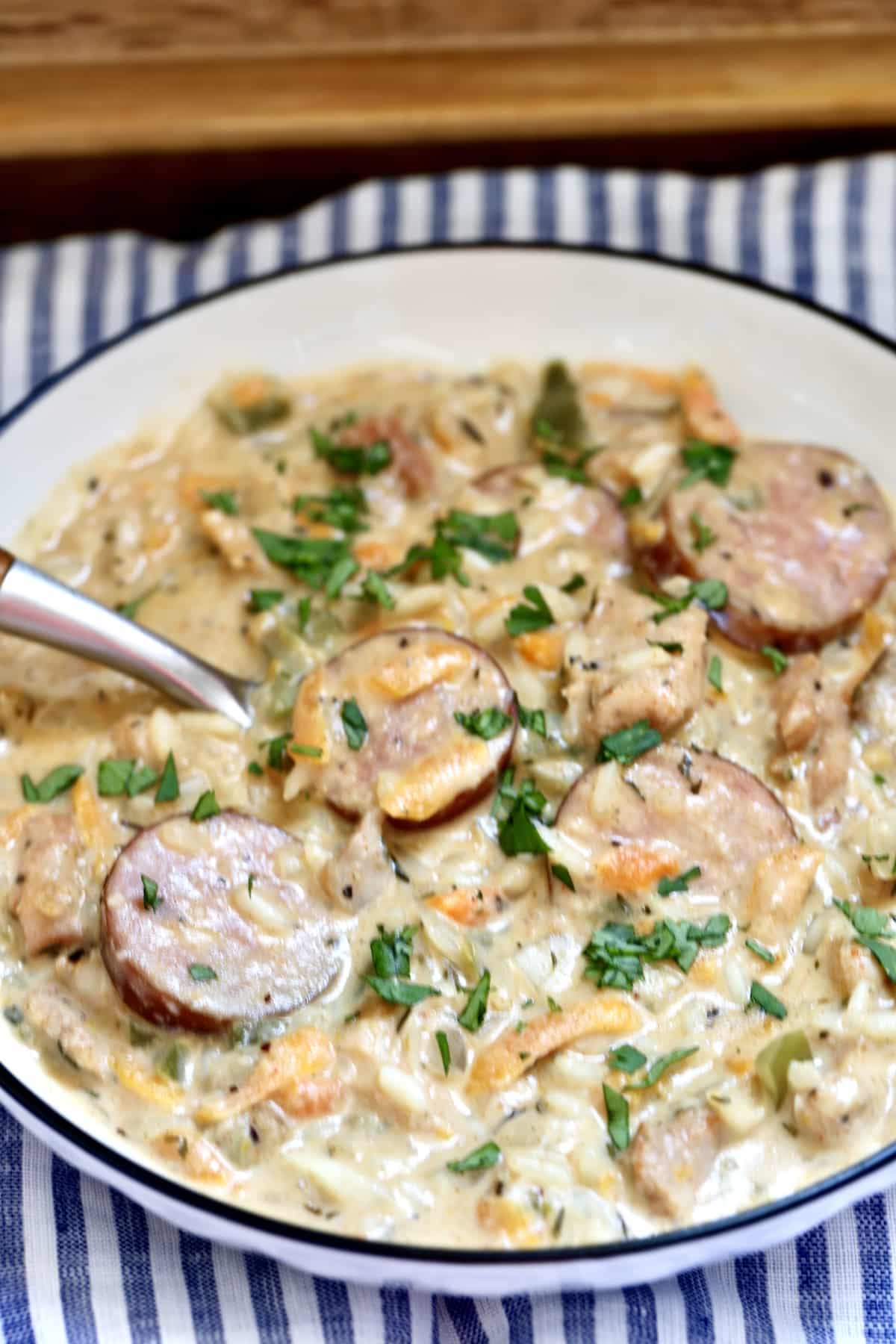 Cheesy rice casserole with chicken and smoked sausage in a bowl with a spoon.