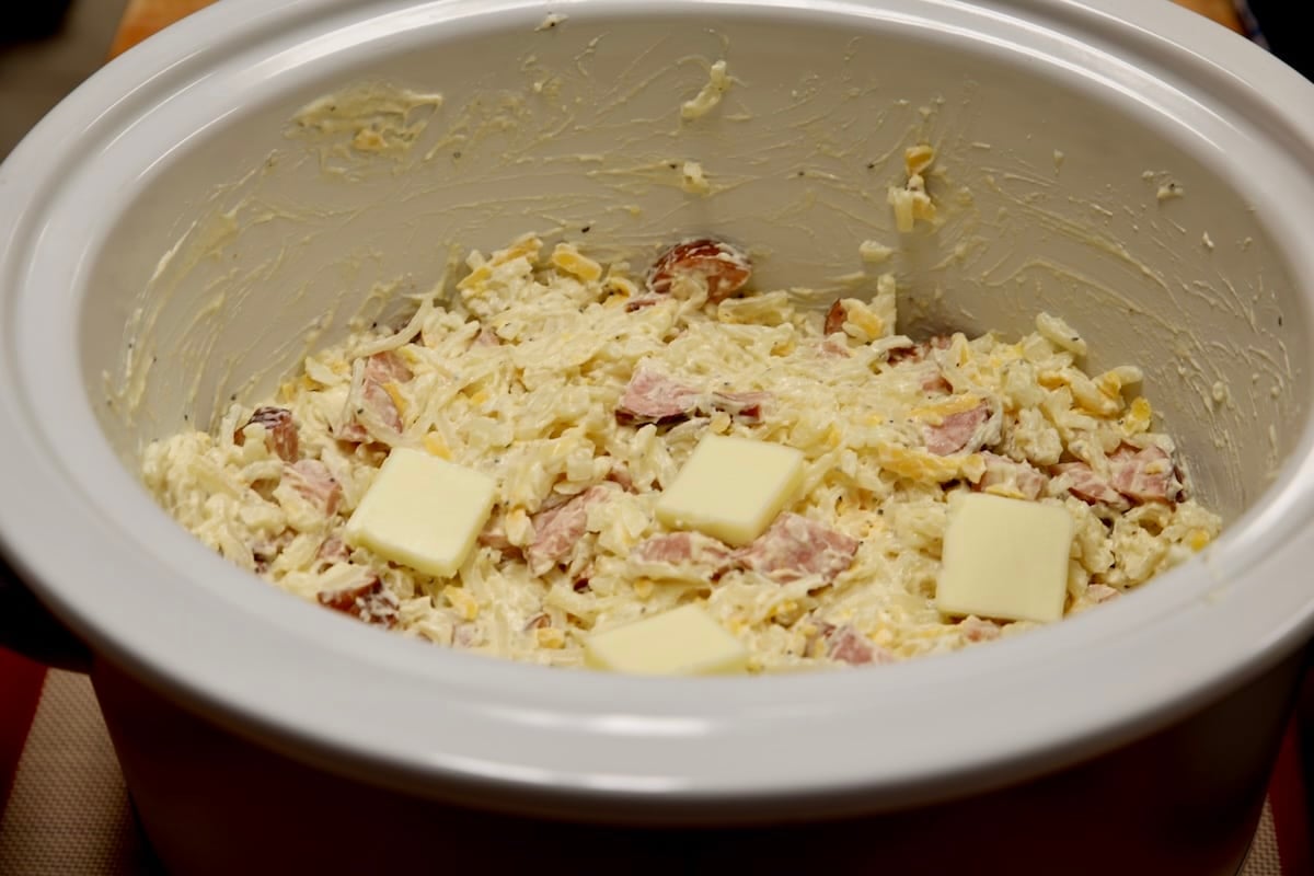 Crock pot with hashbrown casserole ingredients.