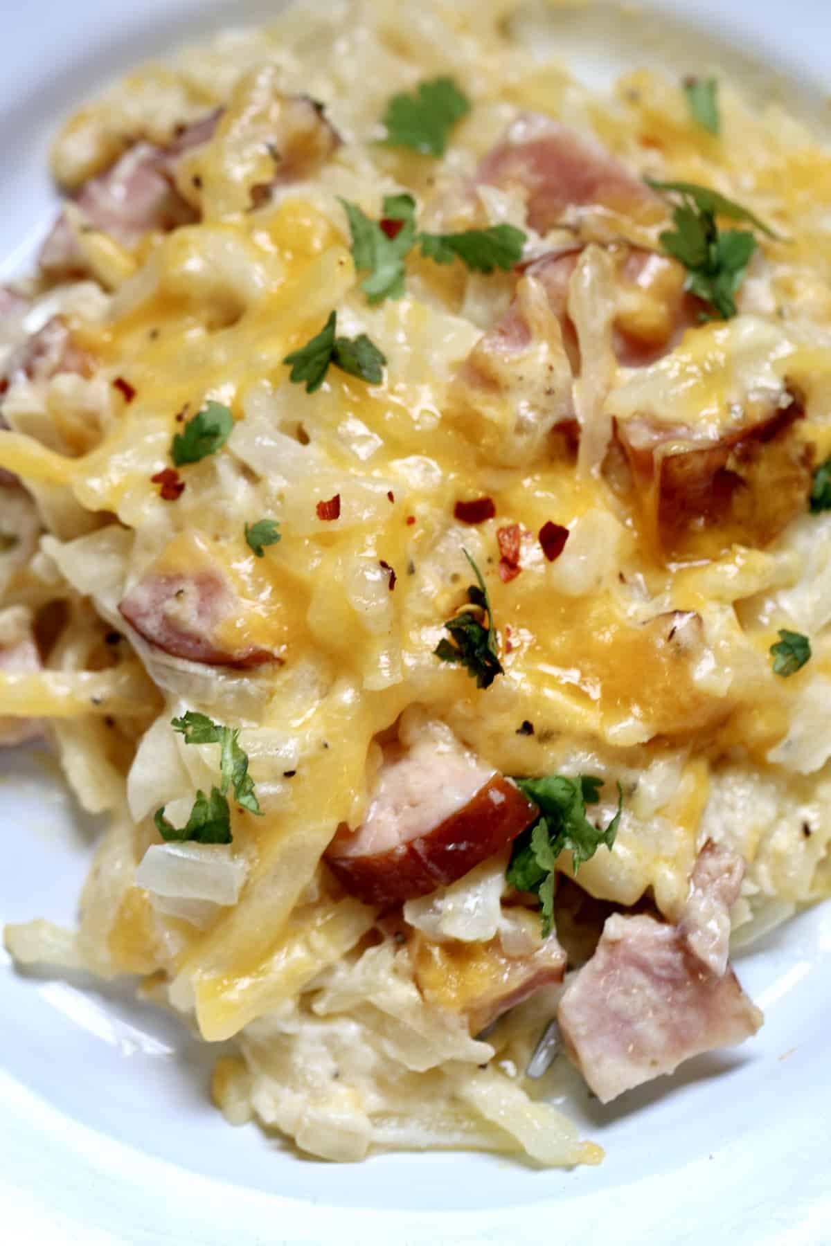 Sausage hashbrown casserole with melted cheese on a plate.