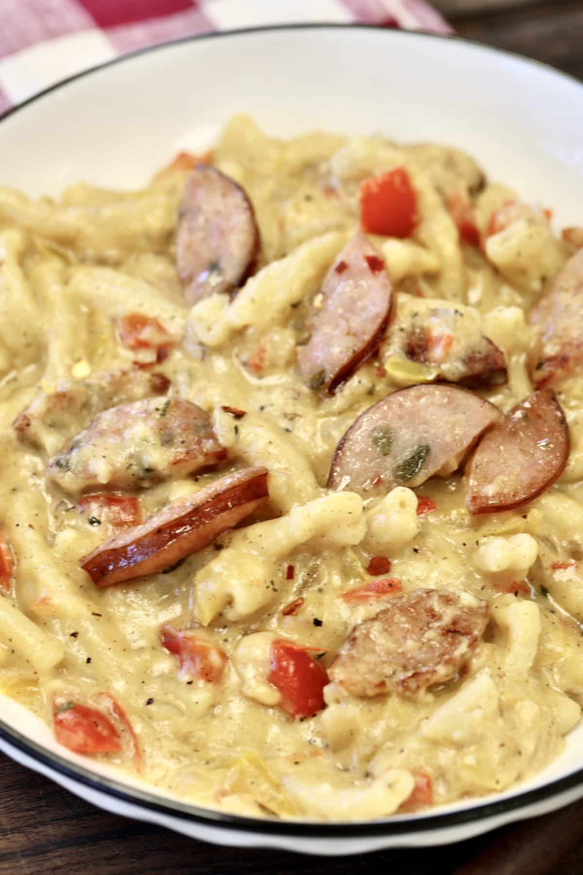 Bowl of smoked sausage pasta with creamy parmesan sauce.